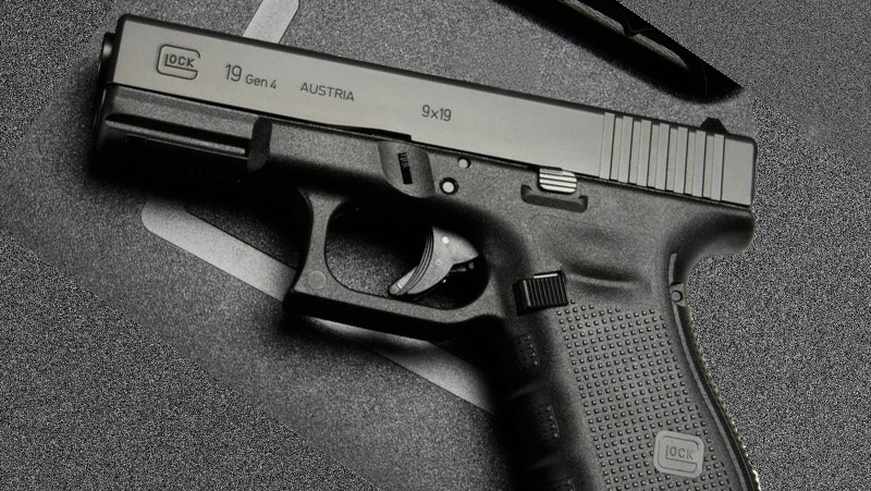 A black Glock G19 Gen 4 on a black surface