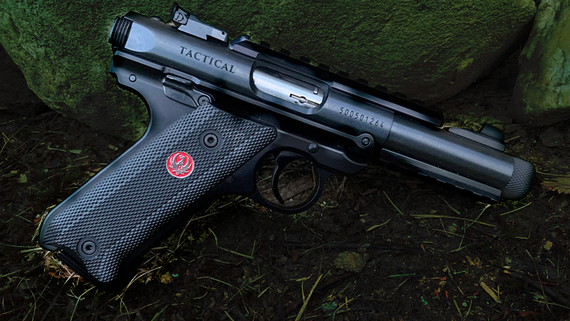 A black Ruger Mark IV, placed by a rock and grassy surface